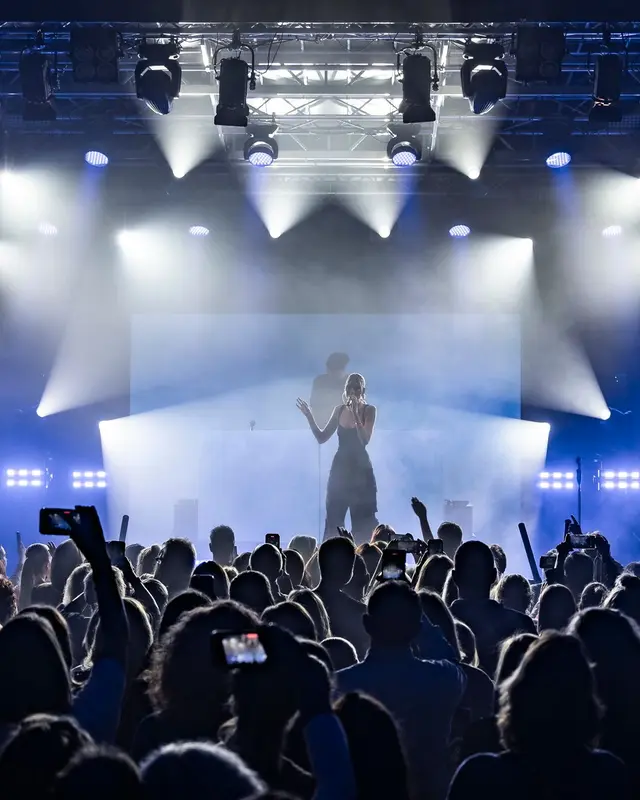 Artist on a blue-lit stage in front of the crowd